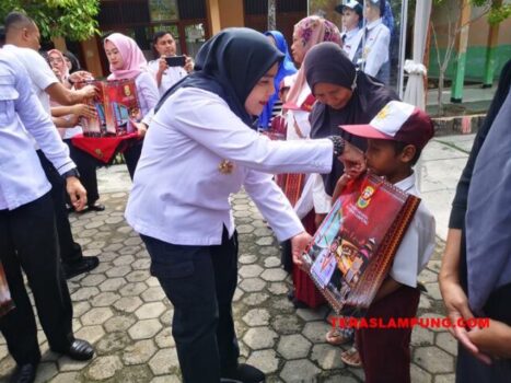Walikota Eva Dwiana menyerahkan peralatan sekolah kepada salah seorang siswa.